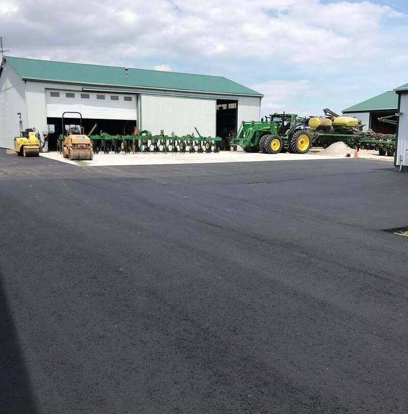 Picture of farm with barns, tractors, and a freshly paved driveway